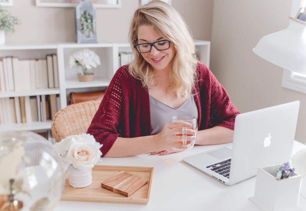 Smiling-woman-with-cup-in-hand-infront-of-laprtop